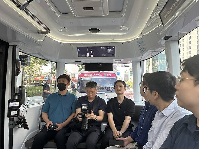 Passengers and a safety officer (left) ride on Seoul's self-driving bus along Cheonggyecheon in Jongno-gu, central Seoul, Tuesday. (Lee Jung-joo/The Korea Herald)