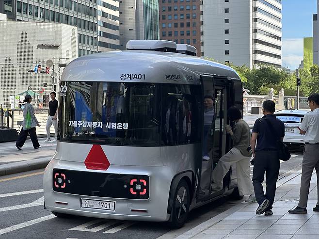 Passengers board the self-driving bus parked on a street near Cheonggyecheon in Jongno-gu, central Seoul, Tuesday. (Lee Jung-joo/The Korea Herald)