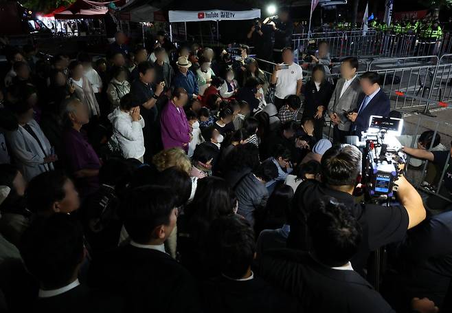 한학자 통일교 총재가 구속된 뒤 23일 새벽 경기도 의왕 서울구치소 앞에 있던 통일교 신도들이 통일교 측 입장 발표를 듣고 있다. 연합뉴스