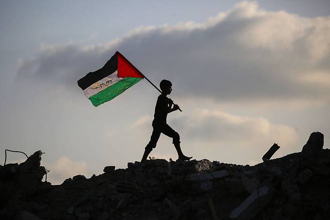<YONHAP PHOTO-0272> TOPSHOT - A displaced Palestinian child waves a Palestinian national flag as he walks on the rubble of a destroyed building at the Bureij camp for refugees in the central Gaza Strip on September 22, 2025. Britain, Australia, Canada and Portugal recognised the State of Palestine on September 21, a historic shift in decades of Western foreign policy that drew swift anger from Israel and a rebuke from the United States. (Photo by Eyad BABA / AFP)/2025-09-23 01:31:16/<저작권자 ⓒ 1980-2025 ㈜연합뉴스. 무단 전재 재배포 금지, AI 학습 및 활용 금지>
