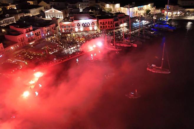 14일(현지시각) 그리스 시로스섬 에르무폴리스에 있는 항구에서 글로벌수무드함대에 소속의 선박 두 척이 도착하자 시민들이 조명탄을 밝히며 환영하고 있다. 로이터 연합뉴스