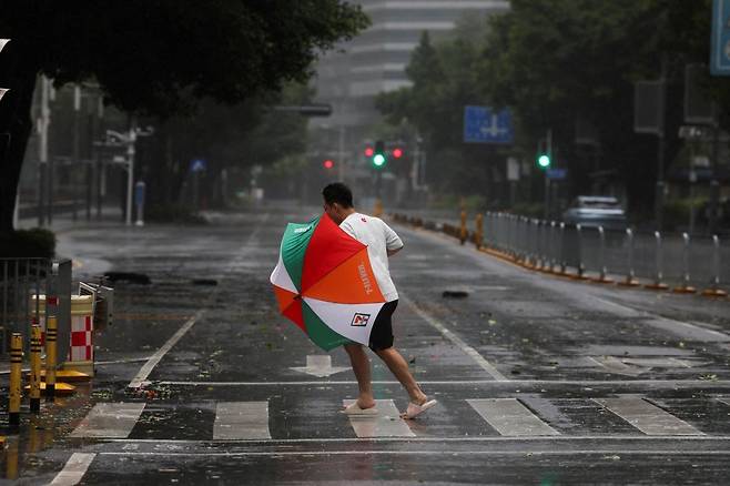 24일 중국 광둥성 선전시의 한 거리에 시민이 태풍 '라가사'의 바람에 맞서 길을 걷고 있다. 로이터연합뉴스