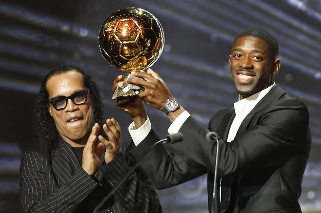 파리 생제르맹 우스만 뎀벨레(오른쪽)가 23일(한국시간) 프랑스 파리 샤틀레 극장에서 열린 2025 발롱도르 시상식에서 2005년 수상자 호나우지뉴에게 남자 선수 부문 트로피를 받고 기뻐하고 있다.  파리 EPA 연합뉴스