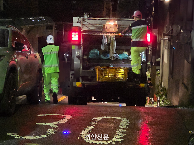 25일 새벽 서울의 한 대학가 인근 골목에서 환경미화원들이 발판에 올라탄 채 이동하고 있다. 우혜림 기자