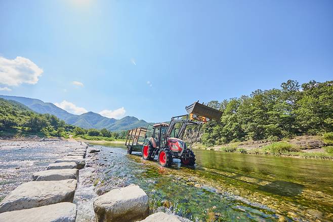 A tractor crosses a river on its way to Menge Village in Andong, North Gyeongsang. [KORAIL TOURISM DEVELOPMENT]