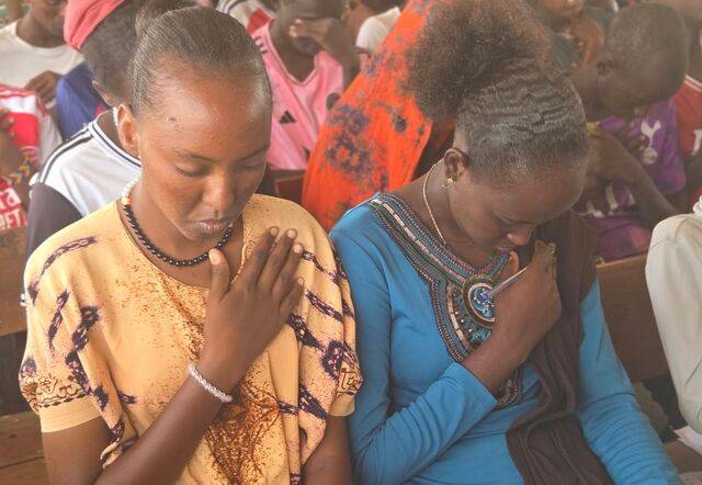 교사인 나씨보 미르기찬(왼쪽)씨가 같은 날 예배에서 친구와 기도하는 장면.