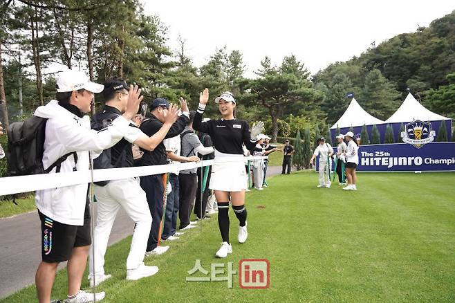 윤이나가 24일 경기도 여주시 블루헤런 골프클럽에서 열린 하이트진로 챔피언십 공식 연습일에 응원하는 팬들과 하이파이브하며 코스를 이동하고 있다. (사진=하이트진로 챔피언십)