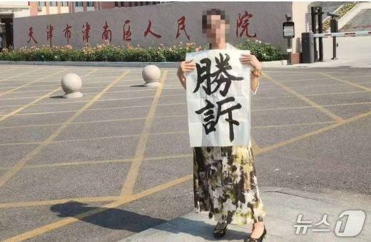 법원 앞의 추이씨. 승소라는 글귀를 들고 있다.  - SCMP 갈무리