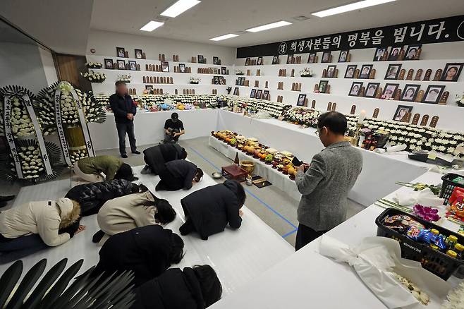 제주항공 여객기 참사 한 달째인 지난 1월29일 무안국제공항 1층 합동분향소에 마련한 합동 차례상 앞에서 유가족들이 절하고 있다. 연합뉴스
