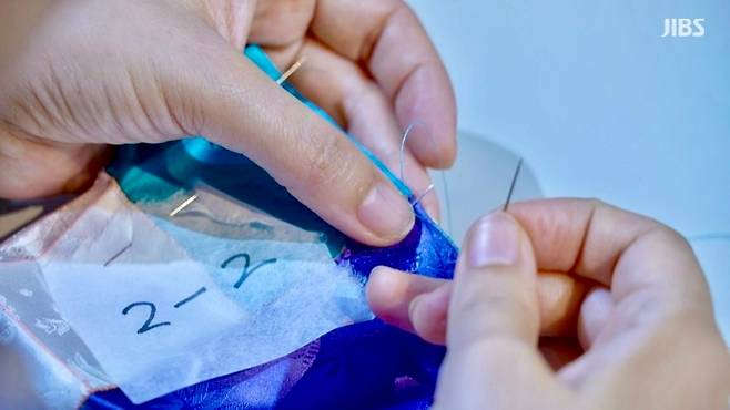 색색의 천 조각을 한 땀씩 잇는 손길. 작은 바늘땀은 모여 따뜻한 이불이 된다.