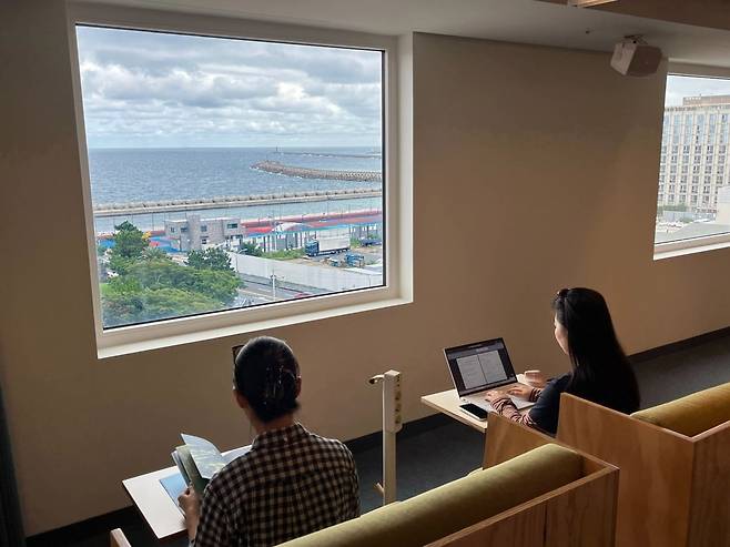 워크 라운지 창가 좌석에서 바다를 보며 일하는 이용객들. 사진=엠지알브이