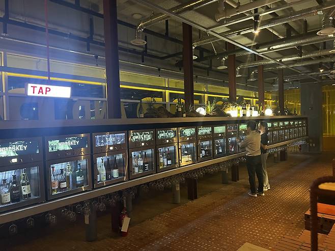 A visitor pours a glass of wine from a tap at Tap and Shop and Bar on Dosandae-ro in Seoul on Sunday. (Kim Jae-heun/The Korea Herald)