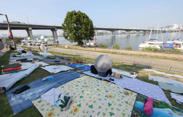 서울 여의도 한강공원 일대에서 열리는 '서울 세계 불꽃축제 2025'를 하루 앞둔 26일 행사장 주변에 한 시민이 돗자리를 펴두고 자리에 앉아 있다. 2025.9.26. 연합뉴스