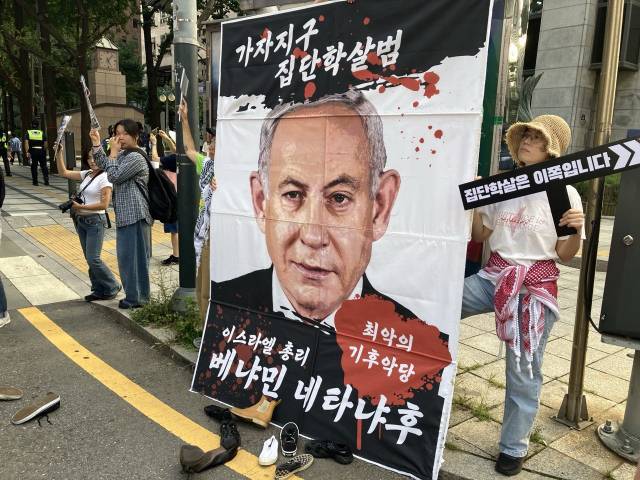 ▲행진 경로에 설치된 베냐민 네타냐후 이스라엘 총리 사진 현수막. 참가자들이 투척한 신발이 앞에 떨어져 있다. ⓒ프레시안(손가영)