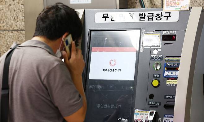 27일 서울 시내 한 지하철역에 설치된 무인민원발급기에서 한 시민이 서류가 발급되지 않자 통화를 하고 있다. 연합뉴스