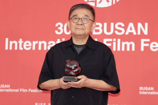 지난 26일 오후 부산 해운대구 영화의전당 야외무대에서 열린 제30회 부산국제영화제 폐막식에서 '루오무의 황혼'으로 경쟁부문 '부산 어워드' 대상을 거머쥔 장률 감독이 기자회견에 앞서 트로피를 들고 사진촬영에 임하고 있다. 정성운 인턴기자