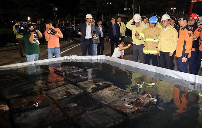 김민석 국무총리가 27일 대전 유성구 국가정보자원관리원 화재 현장을 찾아 소화수조에 담긴 불에 탄 리튬이온 배터리를 살펴보고 있다. 2025.9.27 뉴스1