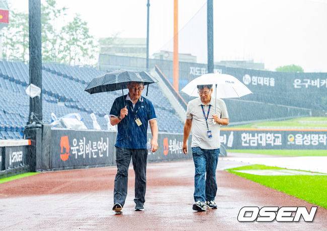 [OSEN=대전, 민경훈 기자] 28일 오후 대전 한화생명볼파크에서 2025 신한 SOL Bank KBO리그&nbsp;한화 이글스와&nbsp;LG 트윈스의 경기가 열릴 예정이지만 그라운드에 비가 내리고 있다.이날 새벽부터 대전 지역에 내린 비가 오전에도 멈추지 않고 있다. 오전 11시 기준으로 시간당 6.8mm 적잖은 강수량을 보이고 있다. 내야에 대형 방수포를 깔았지만 외야와 나머지 그라운드는 빗물로&nbsp;젖었다.박종훈 감독관(왼쪽)이 그라운드 상태를 보고 있다. 2025.09.28 /rumi@osen.co.kr