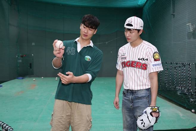 KIA 타이거즈 곽도규(왼쪽)가 지난달 2일 광주 기아챔피언스필드에서 열린 2025 KBO리그 정규시즌 한화 이글스와의 홈 경기를 앞두고 가수 우즈에게 시구하는 방법을 가르쳐 주고 있다. KIA 타이거즈 제공