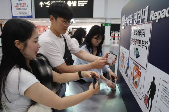 부산 김해국제공항에서 승객들이 보조 배터리에 절연 테이프를 붙이고 있다. 송봉근 기자