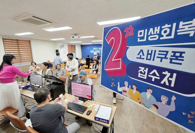민생회복 소비쿠폰 2차 신청 첫날인 이달 22일 한 자치구의 행정복지센터에서 직원들이 주민들에게 소비쿠폰을 지급하고 있다. 연합뉴스