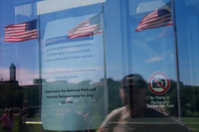 미국 연방정부 셧다운이 시작된 1일(현지시간) 수도 워싱턴DC의 랜드마크 중 하나인 워싱턴기념탑을 찾은 관광객이 건물에 걸린 안내문을 읽고 있다. AP연합뉴스