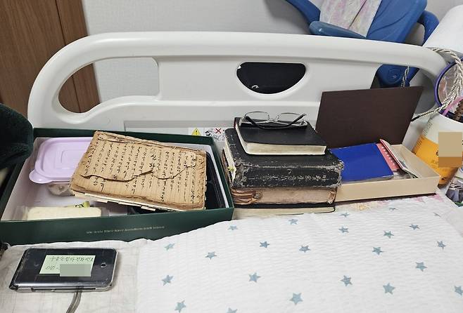 우을순 할머니 침대 머리맡에 놓인 책과 안경들.