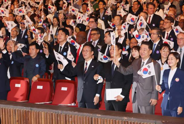 ▲ 김민석 국무총리가 3일 서울 종로구 세종문화회관에서 열린 개천절 경축식에서 참석자들과 만세삼창을 한 뒤 태극기를 흔들고 있다.  연합뉴스
