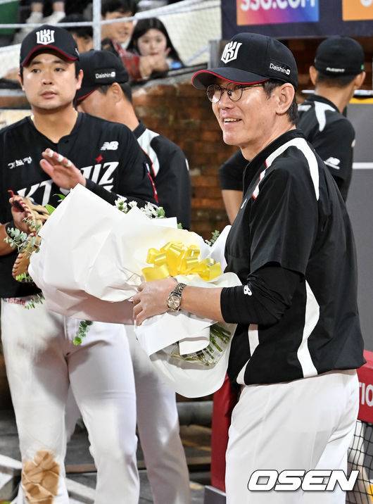 [OSEN=인천, 민경훈 기자] 25일 오후 인천 SSG랜더스필드에서 ‘2025 신한 SOL BANK KBO리그’ SSG 랜더스와 KT 위즈의 경기가 진행됐다.이 경기에서 KT는 SSG에 10-1 완승을 거두며 4연승을 질주했다. 3위 SSG를 잡은 5위 KT는 SSG를 1.5게임차로 맹추격했다. 4위 삼성도 키움전 승리를 거두면서 3위 경쟁은 결과를 예측할 수 없는 혼돈에 빠졌다.&nbsp;경기를 마치고 1000경기를 치른 KT 이강철 감독이 선수들에게 꽃다발을 받고 있다. 2025.09.25 / rumi@osen.co.kr