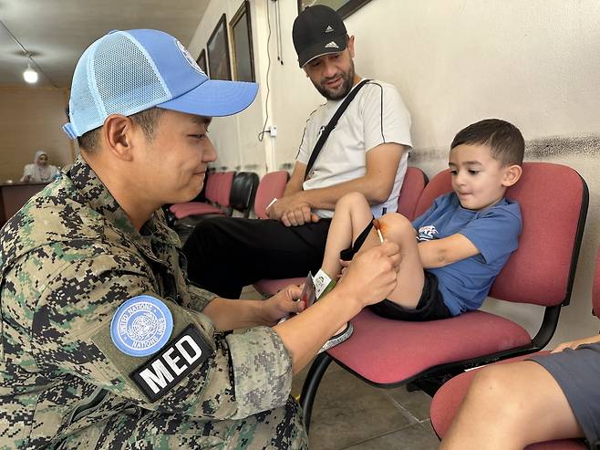 동명부대 의무대 장병이 압바시아 시청에서 찾아가는 대민의료지원 간 현지 아이를 치료하고 있다. [합참 제공]