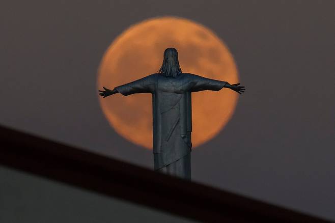 6일(현지 시각) 미국 텍사스주 어빙에 위치한 한 교회 꼭대기의 예수 그리스도 상 뒤로 슈퍼문이 떠오르고 있다. /AP 연합뉴스