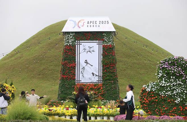 황남동 고분군에 APEC 홍보 꽃 조형물 (경주=연합뉴스) 박세진 기자 = 추석 연휴 닷새째인 7일 경북 경주 황남동 고분군에 설치된 APEC 홍보 꽃 조형물을 배경으로 관광객들이 기념 촬영을 하고 있다. 2025.10.7 psjpsj@yna.co.kr