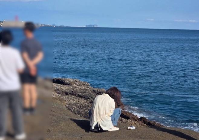 한 여성 관광객이 해안 바위에 앉아 아이의 볼일을 처리하는 장면이 온라인 커뮤니티에 게시됐다. (온라인 커뮤니티 캡처)