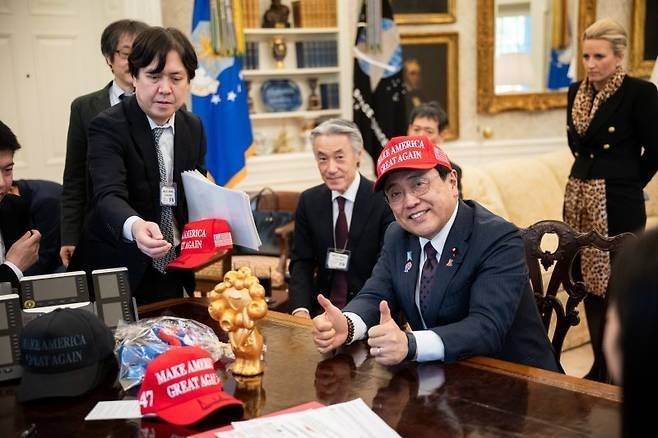 지난 4월 16일(현지시간) 미국 워싱턴DC 백악관 집무실을 찾은 아카자와 료세이 일본 경제재생상이 도널드 트럼프 미국 대통령이 서명해 건네 준 ‘마가’ 모자를 쓰고 있다. 뉴스1