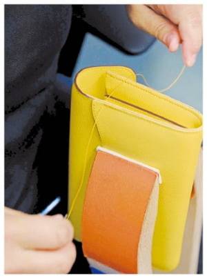 (3)  장인이 소형 가죽 제품의 스티치 작업을 하고 있다.  ©Yann Stofer