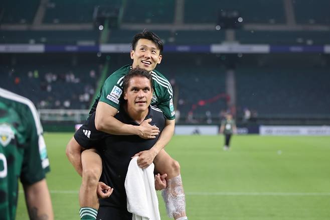 K리그1 전북 현대에서 선수들의 부상 예방과 재활, 치료 전반을 관리하는 지우반 올리베이라 의무팀장은 팬들에게 ‘봉동 화타’라는 별명으로 통한다. 사진은 지우반 팀장이 경기 도중 다친 김태환을 업고 팬들에게 인사하러 가는 모습. 한국프로축구연맹 제공