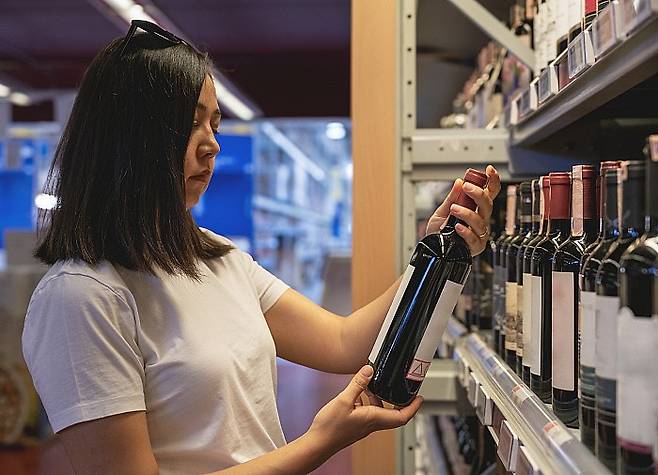 Young woman choosing a wine from the beverage aisle