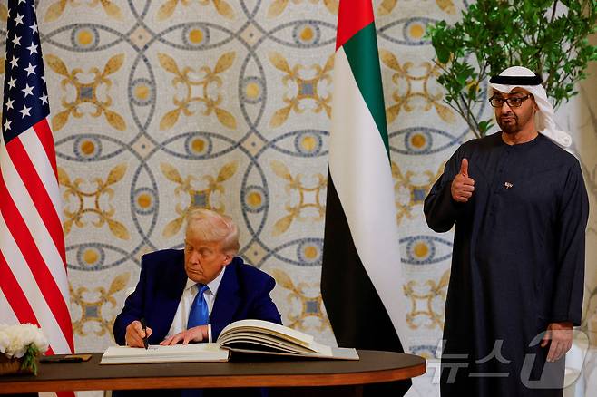 도널드 트럼프 미국 대통령이 지난 5월 15일(현지시간) 아부다비의 대통령 궁에서 방명록에 서명을 하는 동안 셰이크 무함마드 빈 자이드 알 나흐얀 UAE 대통령이 엄지를 치켜 세우고 있다. 2025.05.16 ⓒ 로이터=뉴스1 ⓒ News1 우동명 기자