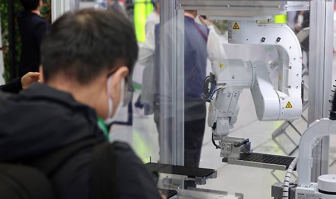 지난 3월 서울 강남구 코엑스에서 열린 2025 스마트공장·자동화산업전를 찾은 한 관람객이 로봇을 활용한 반도체 검사 공정을 살펴보고 있다./뉴스1