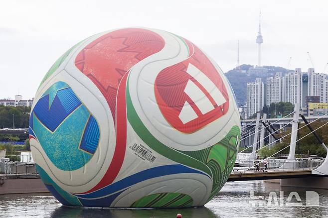 [서울=뉴시스] 김근수 기자 = 12일 서울 서초구 한강시민공원 세빛둥둥섬에 2026년 국제축구연맹(FIFA) 북중미 월드컵의 공인구 '트리온다'(TRIONDA)가 설치돼 있다. 아디다스는 트리온다의 국내 공개를 기념해 서울 세빛둥둥섬에서 'SOAP BALL' 이벤트를 개최한다고 밝혔다.2026년 국제축구연맹(FIFA) 북중미 월드컵의 공인구 '트리온다'(TRIONDA)는 세 개'(Tri)'의 '파도'(Onda)라는 뜻의 트리온다는 월드컵 공동 개최국인 캐나다·멕시코·미국을 기념하는 디자인으로 제작됐다. 빨강, 파랑, 초록의 국가 색상이 중앙 삼각형으로 이어져 세 나라가 하나되는 최초의 월드컵을 의미하며, 미국의 별, 캐나다의 단풍잎, 멕시코의 독수리 등 개최국의 대표 아이콘을 굵직한 그래픽과 엠보싱 기법으로 반영했다. 2025.10.12. ks@newsis.com