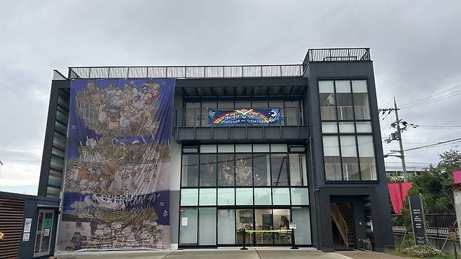 일본 교토 우토로마을 ‘우토로평화기념관\' 외벽에 일제강점기 일본군 비행장 건설을 위해 동원됐다가 이곳에 정착했던 조선인들의 삶을 기록한 대형 걸개그림 ‘피어라, 민들레’가 걸려 있다.