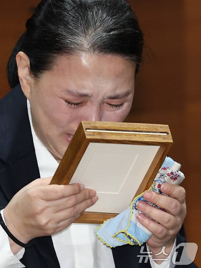 15일 오전 서울시 마포구 상암동 MBC 상암사옥 골든마우스홀에서 열린 안형준 MBC 사장의 기자회견에서 직장 내 괴롭힘을 호소하며 스스로 목숨을 끊은 MBC 기상캐스터 오요안나 씨의 어머니 장연미씨가 명예사원증을 받고 눈물을 흘리고 있다. 2025.10.15/뉴스1 ⓒ News1 박정호 기자