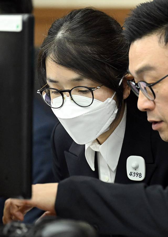 도이치모터스 주가조작 혐의와 통일교 금품수수 의혹 등으로 구속기소된 김건희씨의 첫 재판이 지난달 24일 오후에 열렸다. 김 여사가 법정에 들어와 변호사와 대화하고 있다. [사진공동취재단]