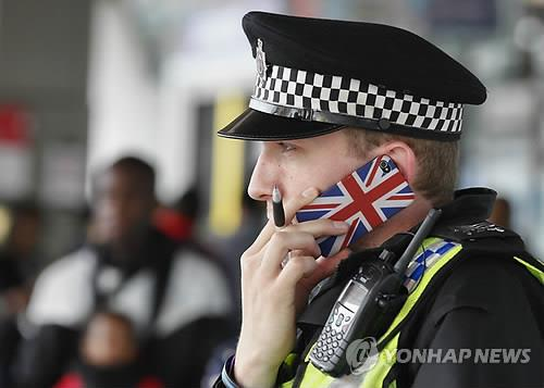 휴대전화로 통화중인 영국 경찰 [사진 = EPA 연합뉴스]