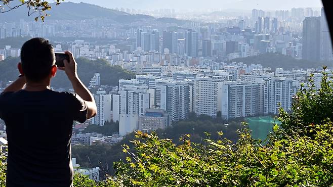 서울 전역 및 경기 12개 지역을  규제지역 지정하고 LTV 40%로 축소하는 10.15 부동산 대책이 발표된 가운데 15일 오전 서울 남산에서 한 시민이 서울 시내 아파트를 바라보고 있다.  이상섭 기자