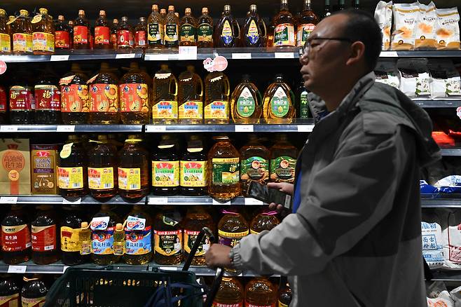 15일(현지 시각) 중국 베이징의 한 슈퍼마켓에서 한 쇼핑객이 판매용 식용유 선반 앞을 지나가고 있습니다. /AFP=연합뉴스