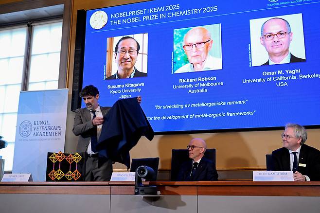 A screen displays the 2025 Nobel Prize laureates in Chemistry, Susumu Kitagawa (Kyoto University, Japan), Richard Robson (University of Melbourne, Australia), and Omar M. Yaghi (University of California, Berkeley, U.S.), as they are announced during a press conference at the Royal Swedish Academy of Sciences in Stockholm, Sweden, October 8, 2025. [REUTERS/YONHAP]