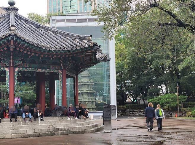 지난 15일 서울 종로구 탑골공원의 정자에 모여 앉은 노인들. 이들 옆으로 외국인 관광객이 지나가고 있다. 공병선 기자