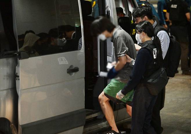 캄보디아 온라인 사기에 가담해 구금된 한국인들이 18일 오전 인천국제공항 제2터미널을 통해 송환돼 호송차에 오르고 있다. 이날 송환에는 경찰 호송조 190여명이 투입됐다. 사진공동취재단