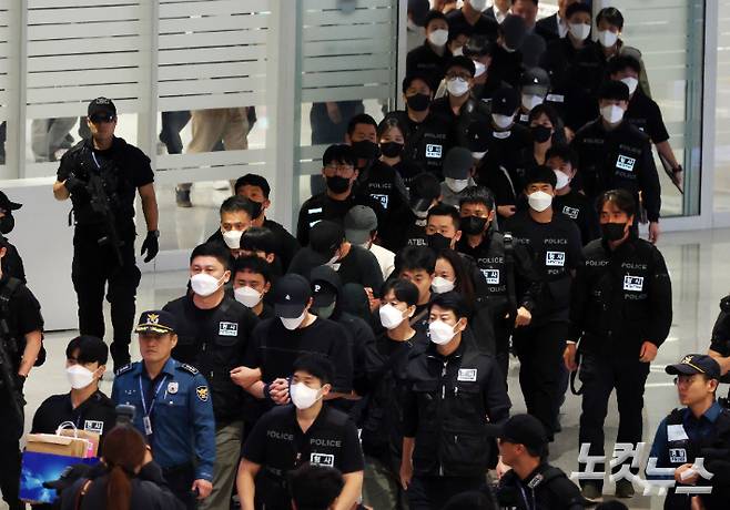 캄보디아에서 보이스피싱(전화금융사기) 등 범죄에 가담했다가 현지 경찰 조사를 받고 이민 당국에 구금됐던 한국인 64명이 18일 오전 인천공항 2터미널을 통해 송환되고 있다. 황진환 기자